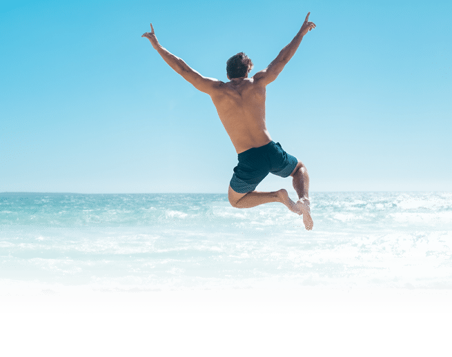 Une personne en short saute joyeusement au-dessus de la plage avec les bras lev s sous un ciel bleu clair. Description g n r e par IA