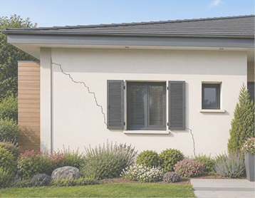 Une fa ade de maison moderne avec des volets gris autour d'une fen tre centrale et une fissure visible sur le mur blanc, entour e de plantes et d'un petit jardin. Description g n r e par IA