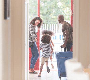 Family Standing By Front Door With Suitcase About To Leave For Vacation